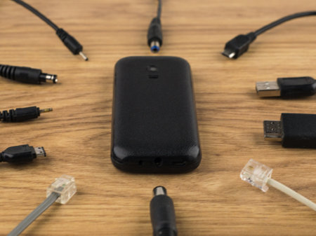 technology generation gap: old dusty mobile phone cover up and lots of plugs that can't connect to...