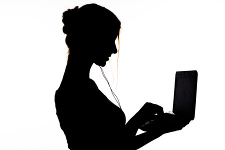 silhouette: girl in profile with headphones, holds a netbook in handsの写真素材