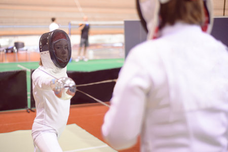 two fencers in white uniforms are training to participate in a duelの写真素材
