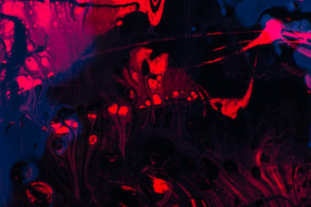 Abstract background with red and blue spots of paint on a black backgroundの写真素材