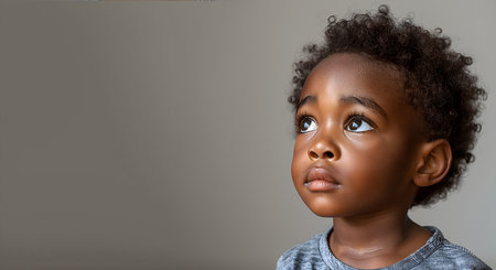 Young black boy with curly hair gazing upwards with hopeの素材