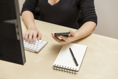 Young Woman Using Her Computer and Smart Phoneの写真素材