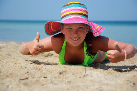 Girl with colorful hats on the beachの写真素材