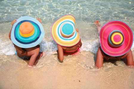 Girls with colorful hats on the beachの写真素材