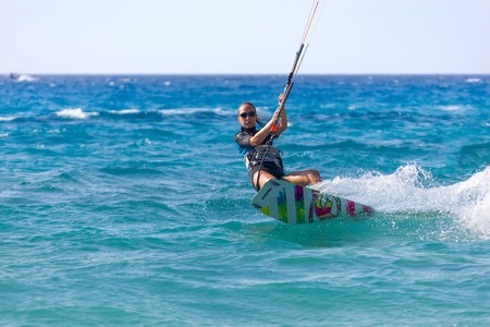 Unidentified young woman kite-surfer rides at famous Milos beach in summer day on July, 26, 2017 in...