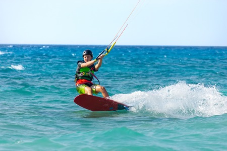 Unidentified young man kite-surfer rides at famous Milos beach in summer day on July, 26, 2017 in Lefkada, Greece.のeditorial素材