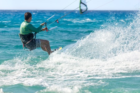 Unidentified man kite-surfer rides at famous Milos beach in summer day in Lefkada, Greece.