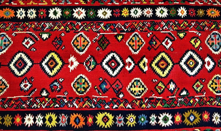 A vibrant red carpet with intricate geometric patterns, showcasing traditional cultural craftsmanship and artistic heritage.の素材