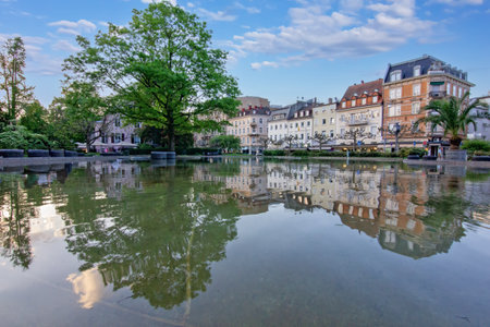 Augustaplatz in Baden-Baden, dominated by the large, glassy surface of a fountain or decorative pond in the foregroundの写真素材