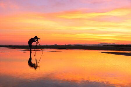 Young Man taking photo with Camera of the view Beautiful sunset at Bang Saphan in winter , Thailandの写真素材