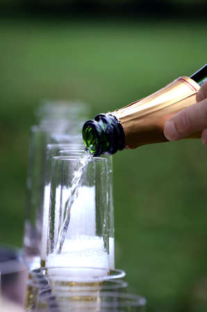 Champagne being poured into glass flute,with the glasses in the background.の写真素材