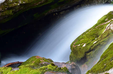 A slow motion blur waterfall over mossy stones.の写真素材