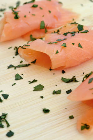 Smoked salmon on a wooden cutting board, decorated with herbs の写真素材