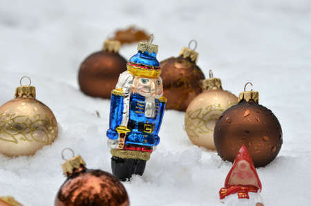 Golden christmas balls in snow with nutcracker.