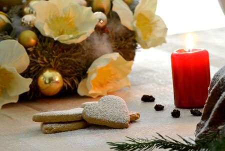 Christmas cookies with candle and christmas decoration in background の写真素材
