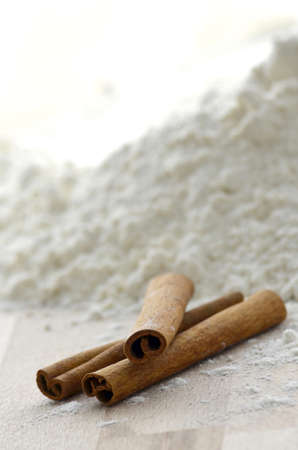 Cinnamon sticks on a wooden table with wheat flour in the background の写真素材