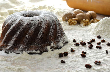 Christmas cake on white flour with raisins  Rolling pin and walnuts in the background の写真素材