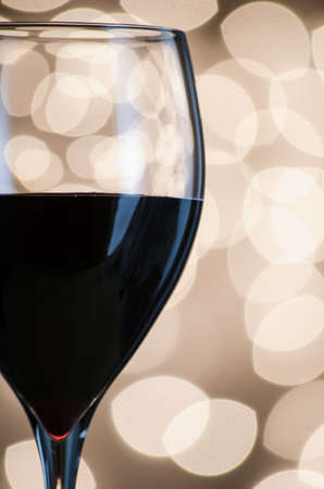 Closeup of a glass of red wine set against a background of Christmas lights  の写真素材