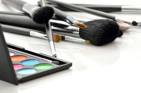 Professional makeup brushes and eye-shadows palette on white background の写真素材