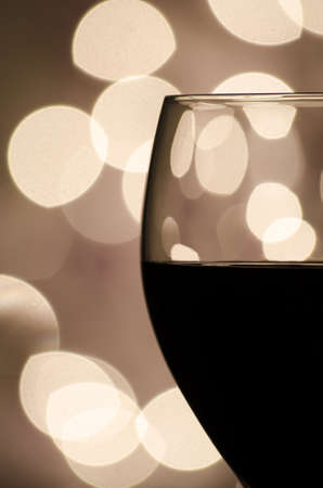 Closeup of a glass of red wine set against a background of blurred lights  の写真素材