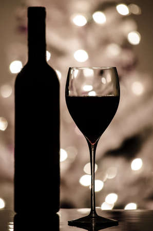 A red wine and bottle silhouette with blurred lights on Christmas tree in background の写真素材