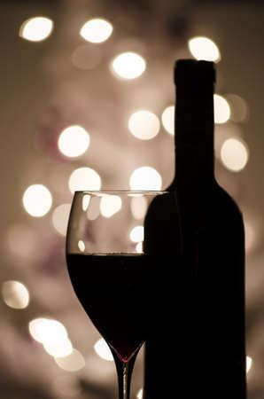 A red wine and bottle silhouette with defocused lights in background.の写真素材
