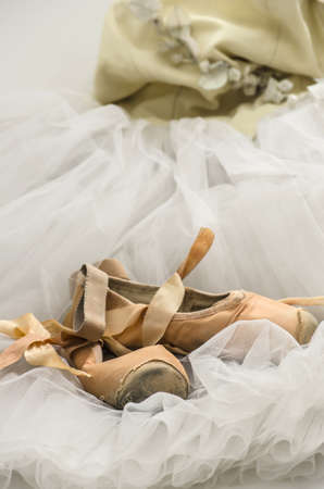 Old pointe shoes lying on a ballet dress の写真素材