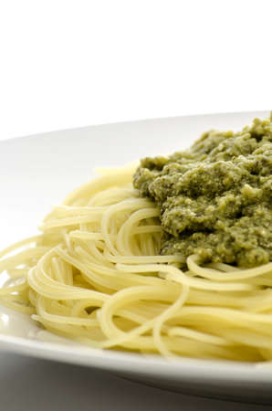 Closeup of italian pasta with pesto sauce served on a white plate の写真素材