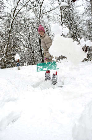 Young woman throwing snow in the air while shoveling の写真素材