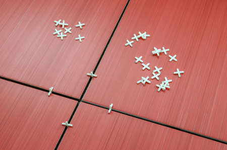 Closeup of unfinished red ceramic tiles with tile spacers spread around の写真素材