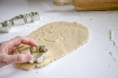Woman making cookies with cutter  Flour and rolling pin in background 