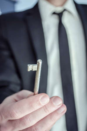 Hand of a man in business suit  offering a key の写真素材