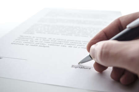 Male hand signing a contract above signature line の写真素材