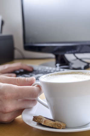 Cropped view of a man drinking coffee while working on computer の写真素材