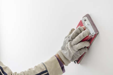 Closeup of a craftsman grinding a wall with sandpaper の写真素材