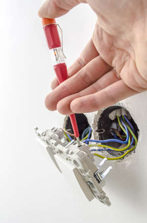 Closeup of an electrician testing electric voltage on a light switch の写真素材