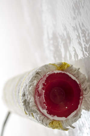 Closeup of a paint roller on a wet white wall の写真素材