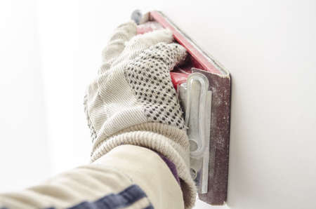 Closeup of a male hand polishing a wall with sandpaper の写真素材