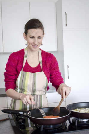 Happy young woman cooking dinner in the kitchen の写真素材