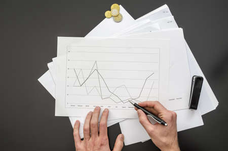 Top view of male hand holding a pen over a business document の写真素材