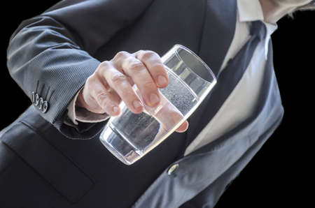 Business man offering a glass of water  Cropped view over black background の写真素材