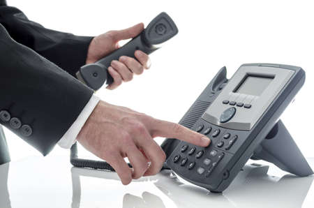 Male hand dialing number on a black phone against a white background の写真素材