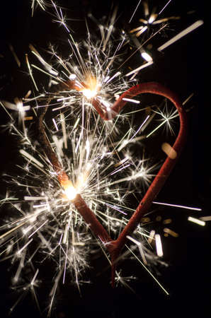 Burning heart with sparkles on a dark background の写真素材