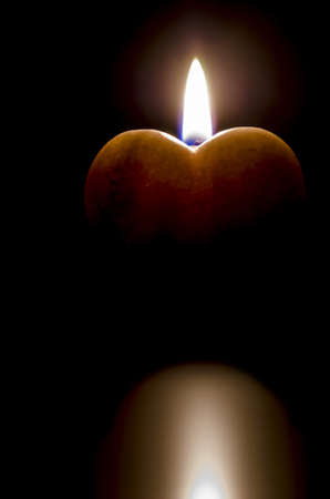 Heart with a candle flame  Isolated over black background の写真素材