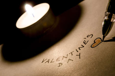 Writing a valentine text on a paper by a candlelight の写真素材