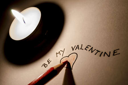 Pencil writing a Be my Valentine note- romantic scene with candle の写真素材