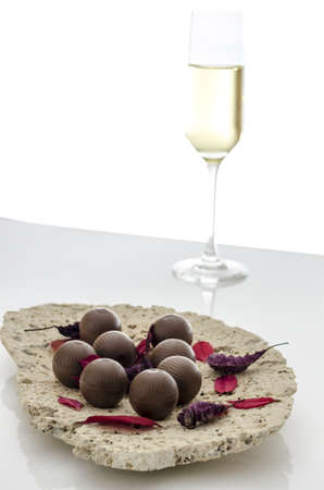 Chocolate candies decorated with leaves on a plate made of stone の写真素材