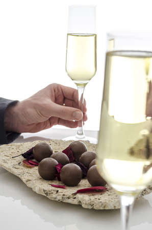 Male hand holding a glass of wine on a white table の写真素材