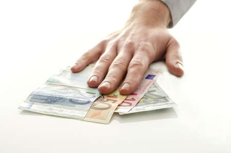 Man holding his hand over Euro money banknotes on a white table の写真素材