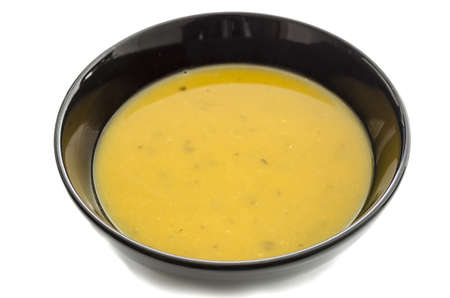 Pumpkin soup in black bowl isolated over a white background の写真素材